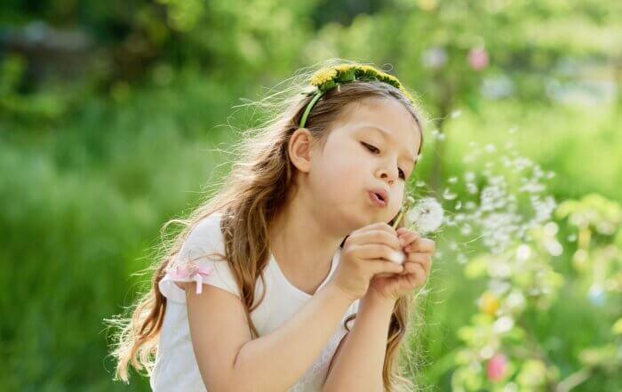 girl blowing dandelions flower selective focus. Allergy season