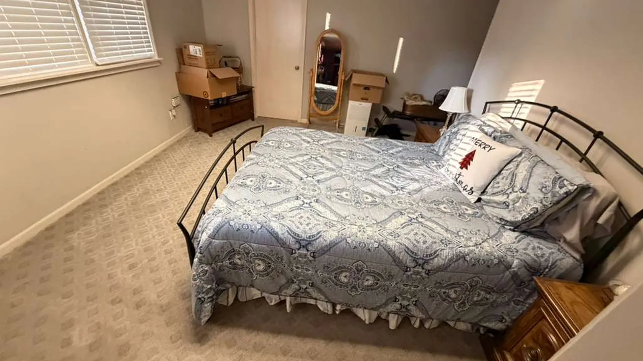 Rental bedroom with an iron bed frame made up and the floor vacuumed for the next guest