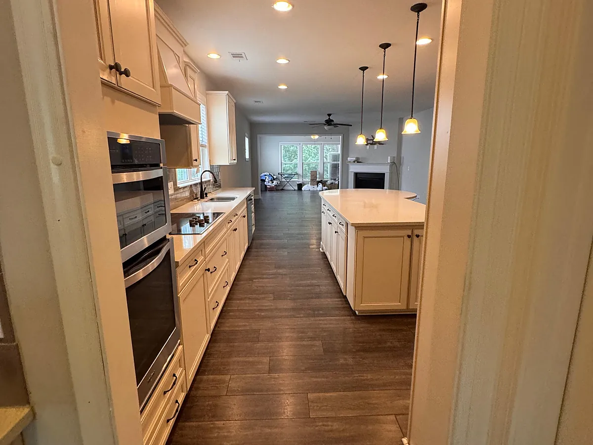 Pale galley kitchen with wall ovens and hardwood floors in a Metro Atlanta home after a cleaning visit