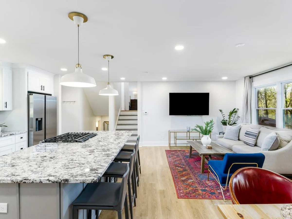 Open-plan kitchen and living area with a stone island and hardwood floors